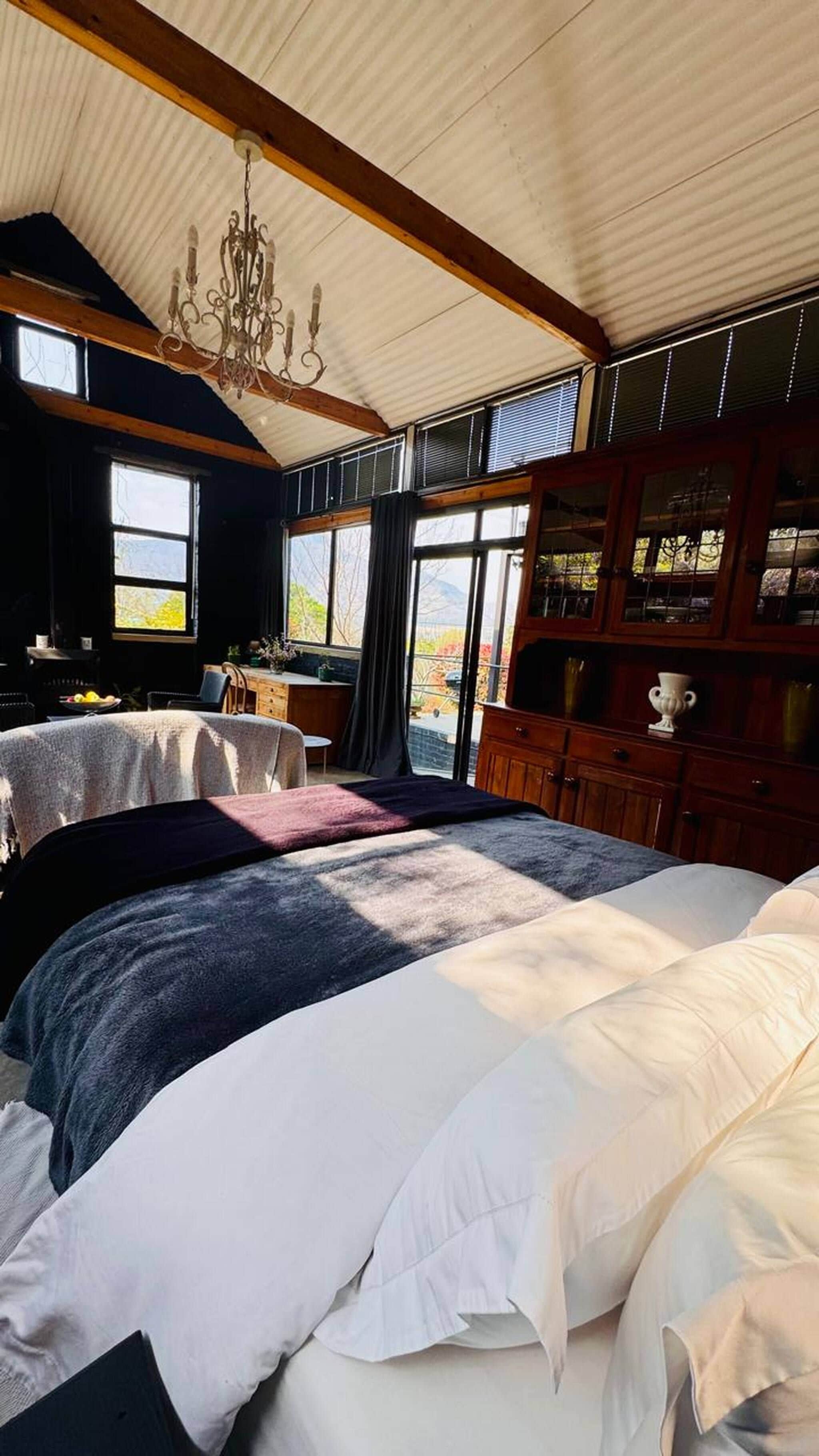 A bedroom with a large bed, a wooden desk, and a chandelier.