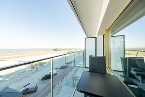 A balcony with a view of a beach and a road with parked cars. - Studio by the Sea With Stunning Terraces (Blankenberge)