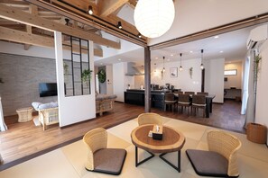 Un grand espace de vie comprenant un coin repas, une cuisine et un téléviseur fixé au mur.