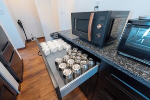 A kitchen with a microwave, a coffee machine, and a drawer with stainless steel containers. - Villa Arco Miyakojima (Miyakojima City)