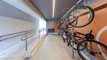 Un support à vélos avec plusieurs vélos, une pancarte indiquant « OUTILS », et un sol carrelé avec une main courante.