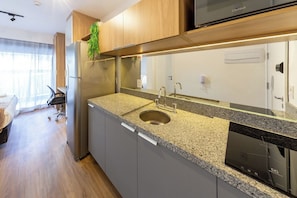 Ett modernt kök med ett kylskåp i rostfritt stål, en bänkskiva i granit och en inbyggd diskmaskin.