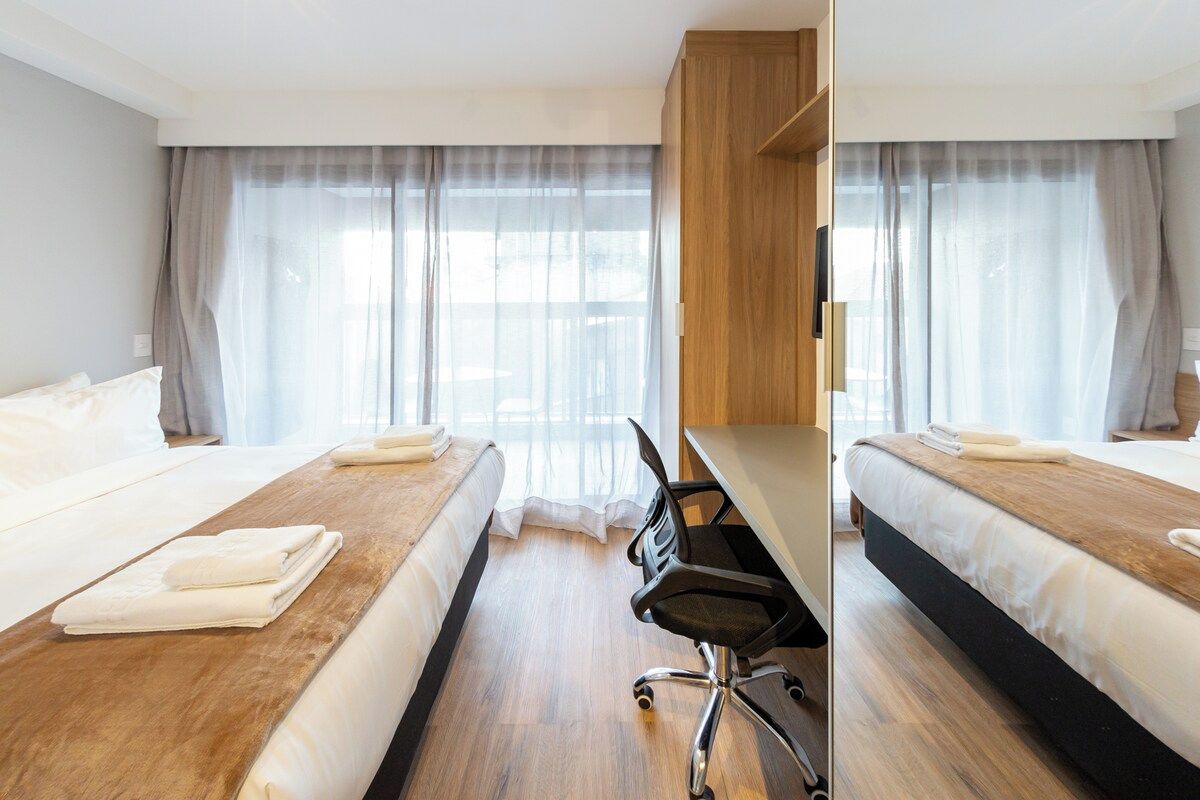 Ett hotellrum med två sängar, ett skrivbord och en stol.