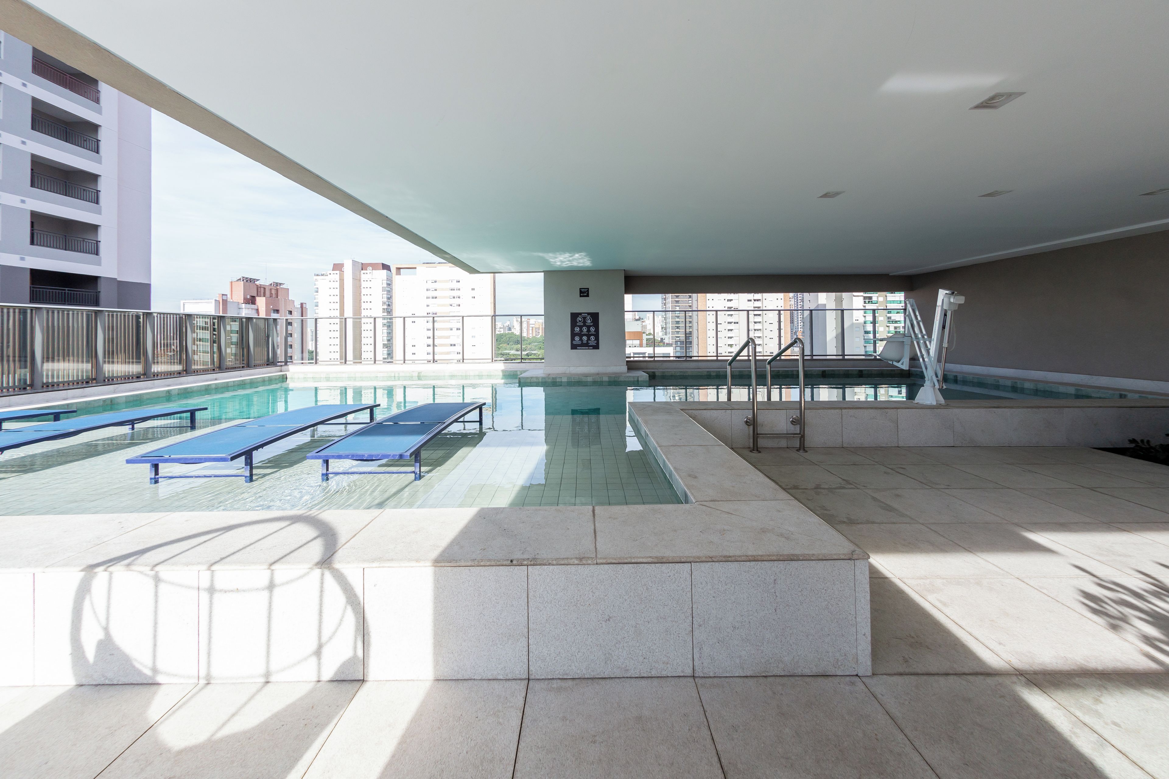 Une piscine sur le toit, dotée de chaises longues et offrant une vue sur les bâtiments environnants.