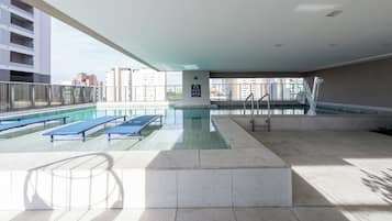 Une piscine sur le toit, dotée de chaises longues et offrant une vue sur les bâtiments environnants.