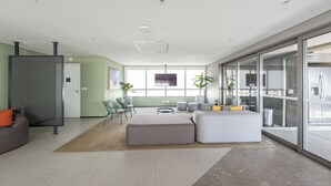 Un interior moderno con una zona de estar, kitchenette y un ventanal grande.