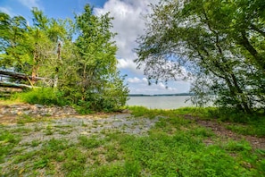 A natural landscape with a lake, trees, and a stone wall. - Riverfront Living (Clifton)