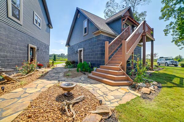 A two-story house with a stone pathway leading to a wooden staircase.