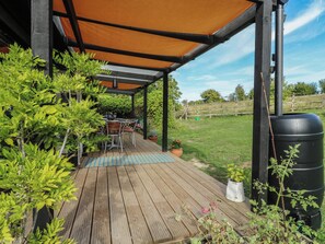 An outdoor patio with a wooden deck, a covered seating area, and potted plants. - Orchard Lodge (Dover)