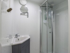 A bathroom with a glass-enclosed shower, a white sink, and two wall-mounted mirrors. - Orchard Lodge (Dover)