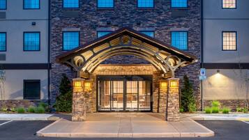 A building entrance with a stone archway, large glass doors, and a parking sign.