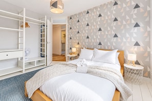 Ein Hotelzimmer mit einem Bett, Nachttischen, einem Kleiderschrank und einer Wand mit geometrischem Muster.