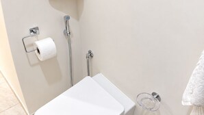 A bathroom with a toilet, a towel rack, and a toilet paper holder. - Vrbo Property (Napoli)
