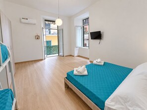 Et hotelværelse med seng, fjernsyn, balkon og aircondition.