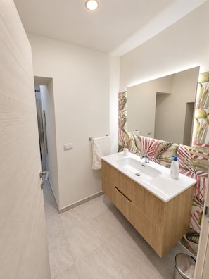 A modern bathroom with a large mirror, a white sink, and wooden cabinetry. - Pinuccia and Totore Sweet Home (Napoli)