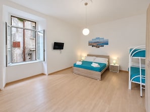 A bedroom with a bed, bedside tables, a TV, a window, and a bunk bed. - Pinuccia and Totore Sweet Home (Napoli)