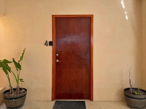 Puerta de madera con el número 4 en la parte superior, flanqueada por dos macetas.