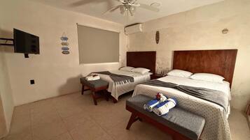 A hotel room with two beds, a ceiling fan, a flat-screen TV, and a window.