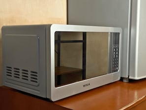 Un horno microondas con panel de control digital y puerta transparente.