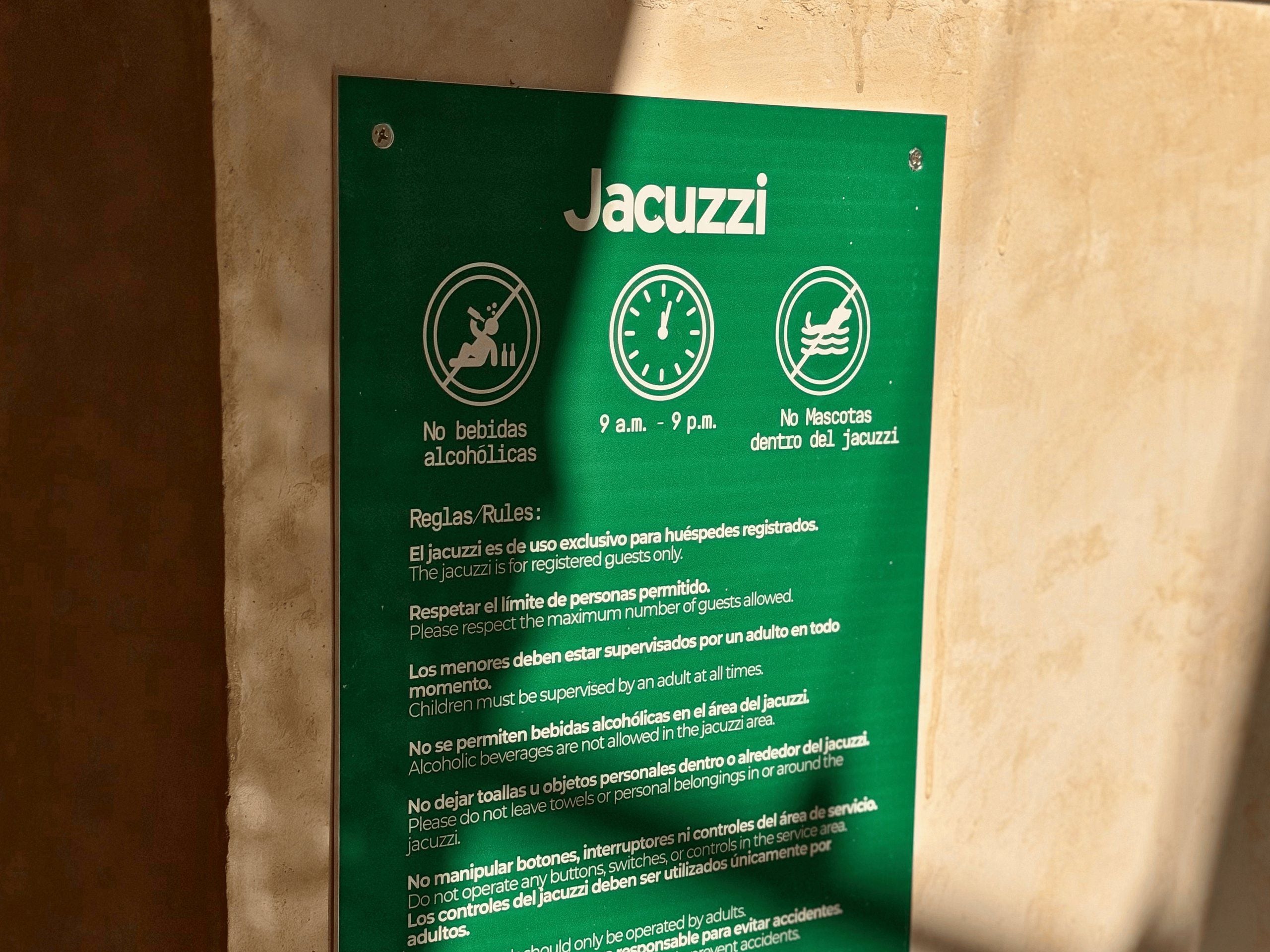 Segnaletica verde con le regole per l'area idromassaggio: divieto di alcolici, divieto di animali domestici e orario di utilizzo dalle 9:00 alle 21:00.