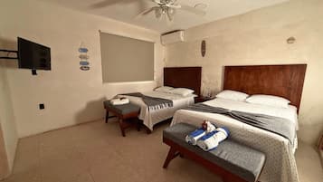Een hotelkamer met twee bedden, een plafondventilator, een flatscreen televisie en een raam.