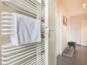 Habitació d'hotel amb una barra tovalloles blanca, una porta que dona a una altra habitació i un petit cendrer.