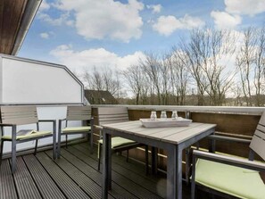 An outdoor deck with seating and a table, overlooking a landscape with trees and a clear sky. - Holiday Home With 2 Bedrooms (St. Peter-Ording)