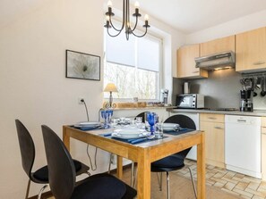 Cuina moderna amb taula de dinar preparada per a quatre persones, equipada amb cafetera, torradora i microones.