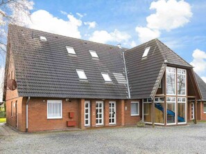 A two-story building with a sloped roof, multiple windows, and a visible staircase leading to an upper level. - Holiday Home With 2 Bedrooms (St. Peter-Ording)