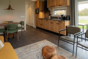 Una cocina moderna con armarios de madera, horno integrado y ventana con vistas a un jardín.