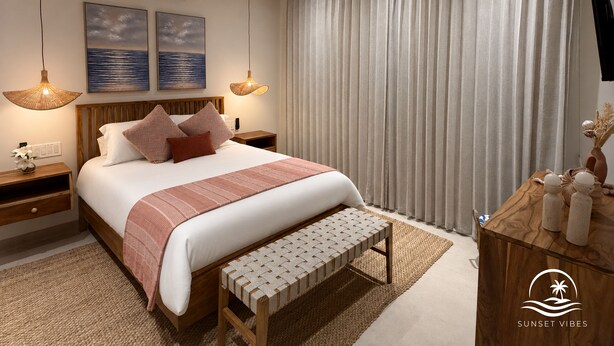 A modern bedroom with a large bed, a wooden bench, a ceiling fan, and a view of the sea through curtains. - New AC Villa in Hacienda Pinilla, 4BR, 4BA, Private pool& parking (Hacienda pinilla)
