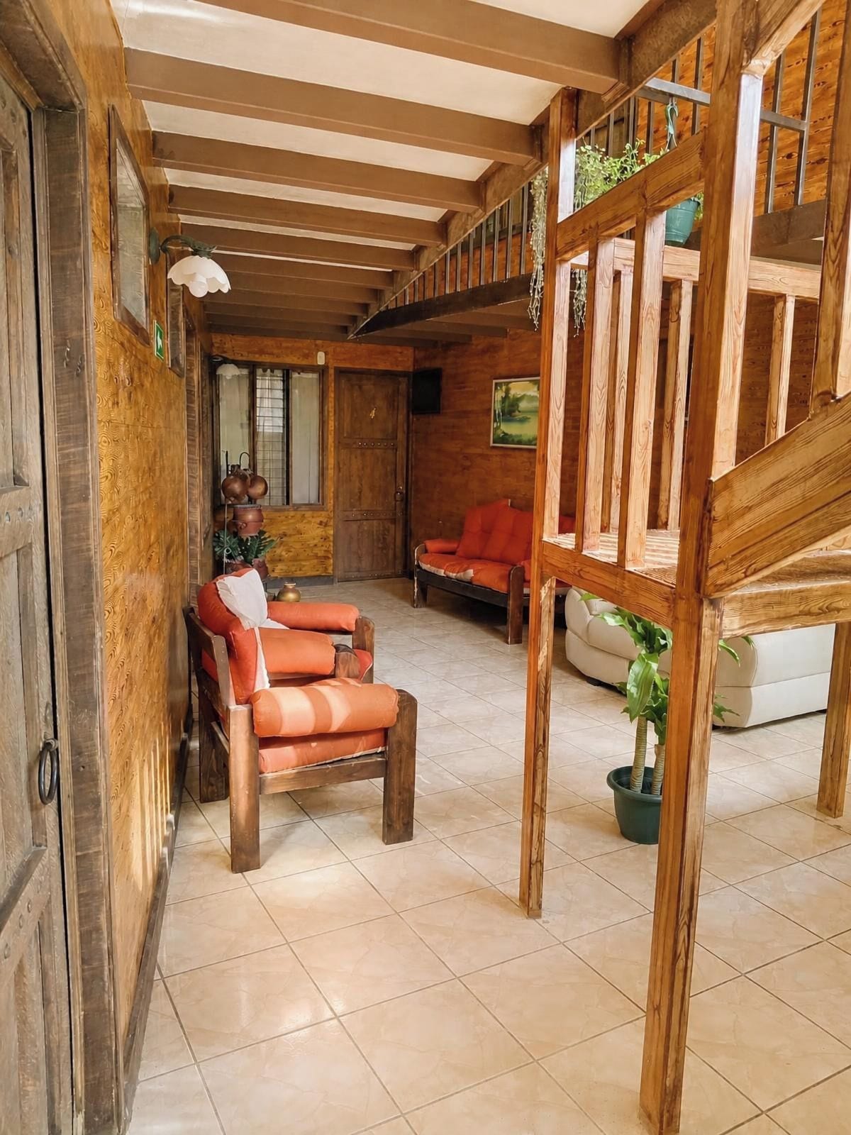 Un interior de madera con una escalera, un sofá y una mesa de comedor.