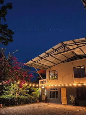 A two-story building with a balcony, a sign that reads 'DOM ROBERTO HOTEL,' and a string of lights along the front.