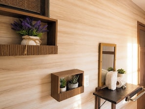 A wooden wall with built-in shelves holding plants and a mirror.