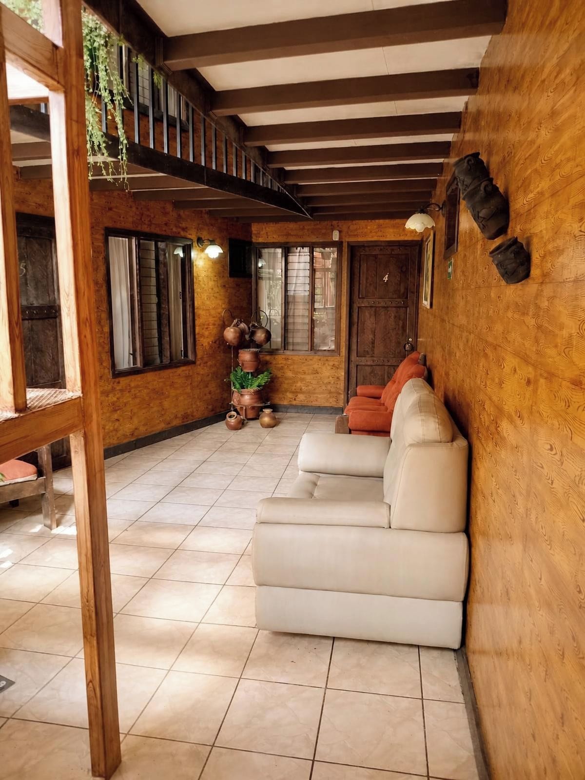 Una habitación acogedora con techo de madera, un sofá blanco y una puerta con un número.