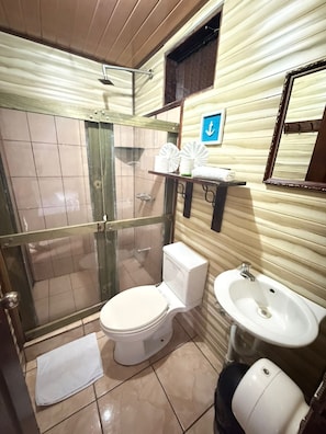 A bathroom with a toilet, a sink, and a shower area. - Hotel Don Roberto (San Isidro de El General)