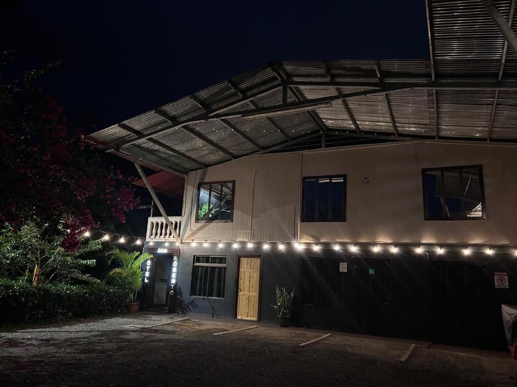 A building with a covered entrance, a balcony, and a series of lights along the front.