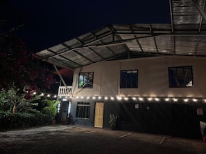 Un edificio con un porche cubierto, un balcón y una serie de luces a lo largo de la fachada.