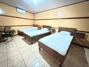 A room with two beds, a chair, a desk, and an air conditioning unit. - Hotel Don Roberto (San Isidro de El General)