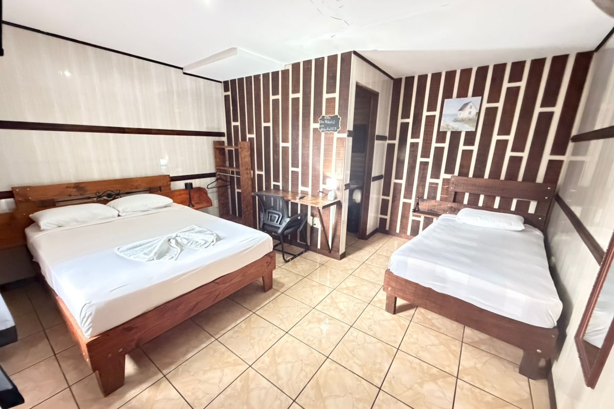 A hotel room with two beds, a desk, and a wardrobe.