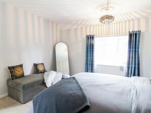 Ein Schlafzimmer mit einem Bett, einem Spiegel, einem Fenster mit Vorhängen und einer Uhr auf einem Kissen.