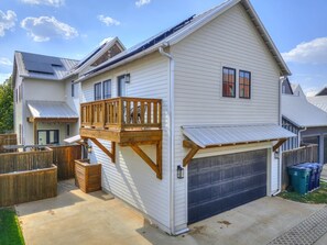 Une maison à deux étages avec un garage, une terrasse en bois et une cour arrière clôturée.