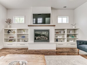 A living room with a fireplace, white shelving, and a blue armchair. - Beautiful 4 Bed 2.5 Bath Home in Wheeler District (Oklahoma City)