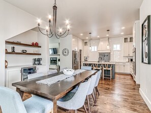Une cuisine moderne dotée d’un îlot central, de planchers en bois et de luminaires suspendus.
