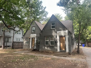 A two-story residential building with a front porch and a small front yard.