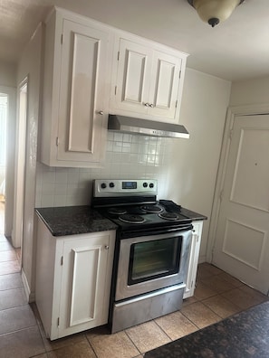 A kitchen with white cabinets, a stainless steel range hood, and a built-in oven.