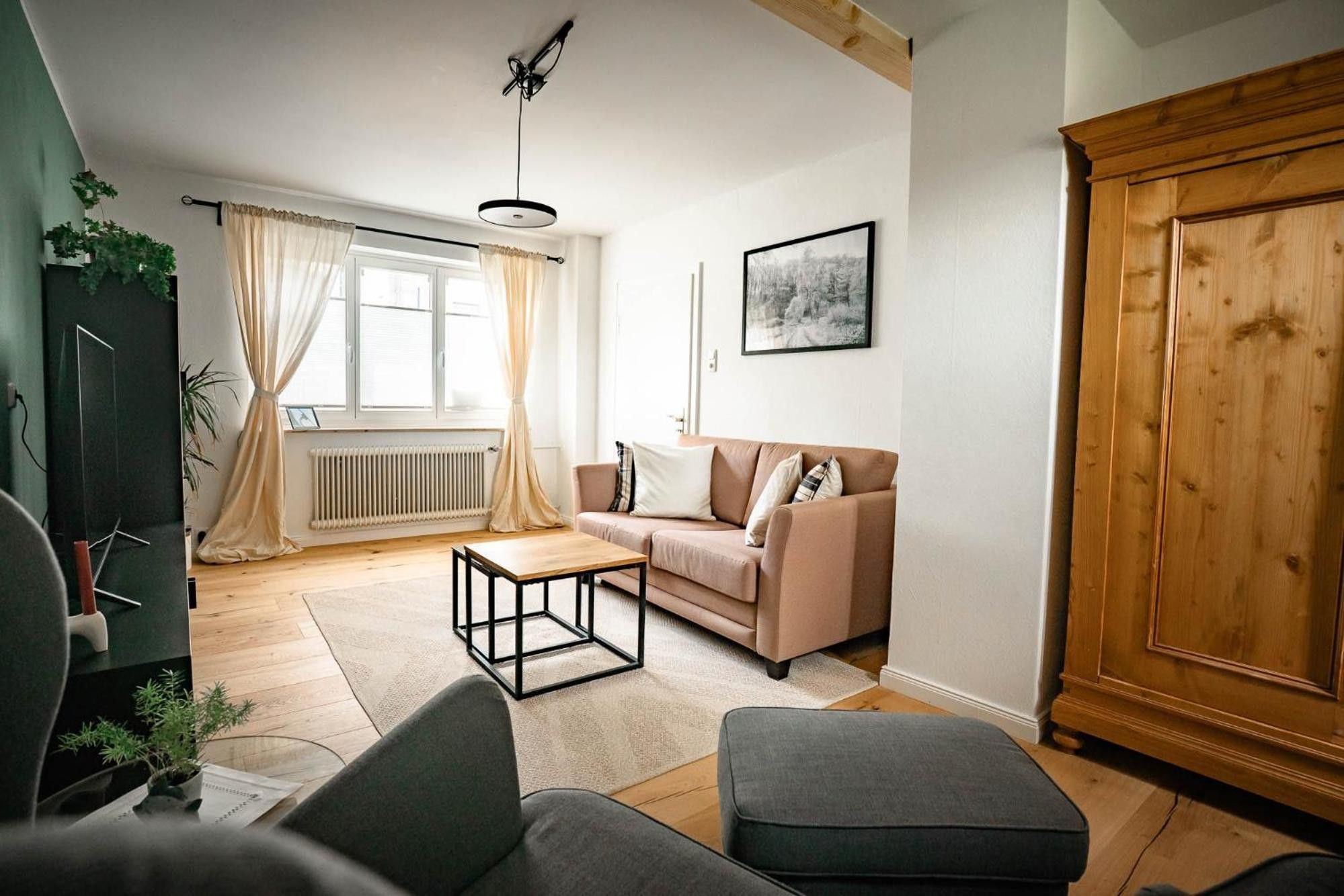 Ein Wohnzimmer mit Sofa, Hocker, Couchtisch und einem Holzschrank.