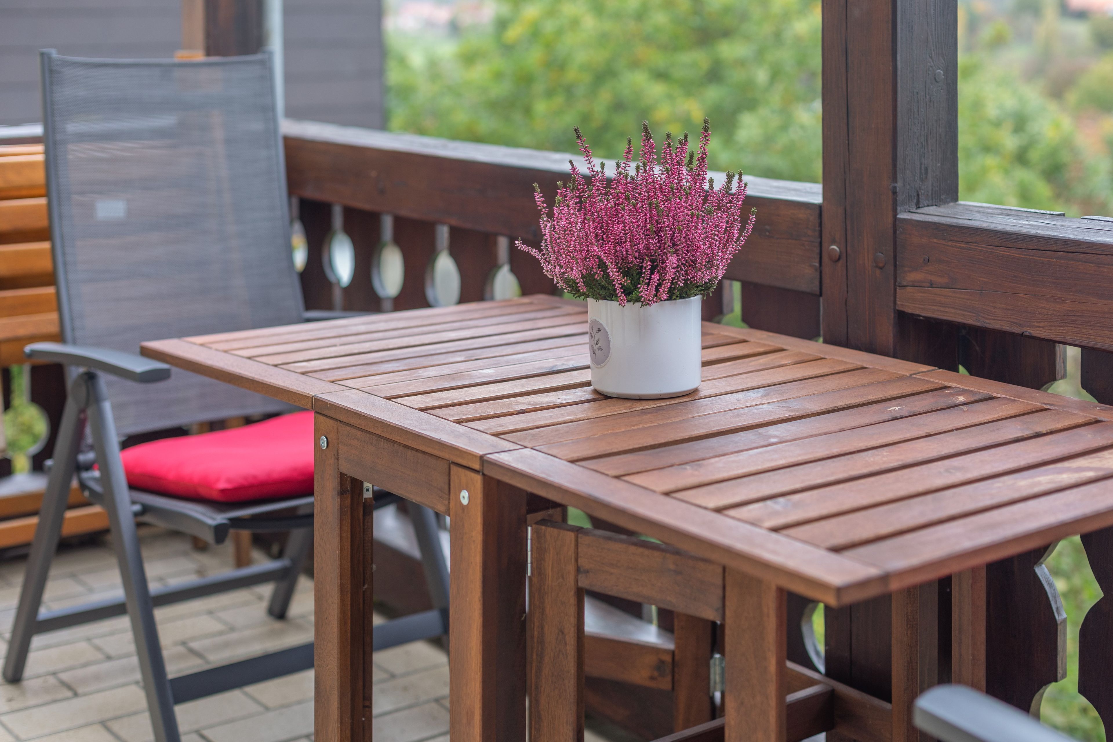 A wooden table with a potted plant on it, a red cushioned chair, and a wooden bench.