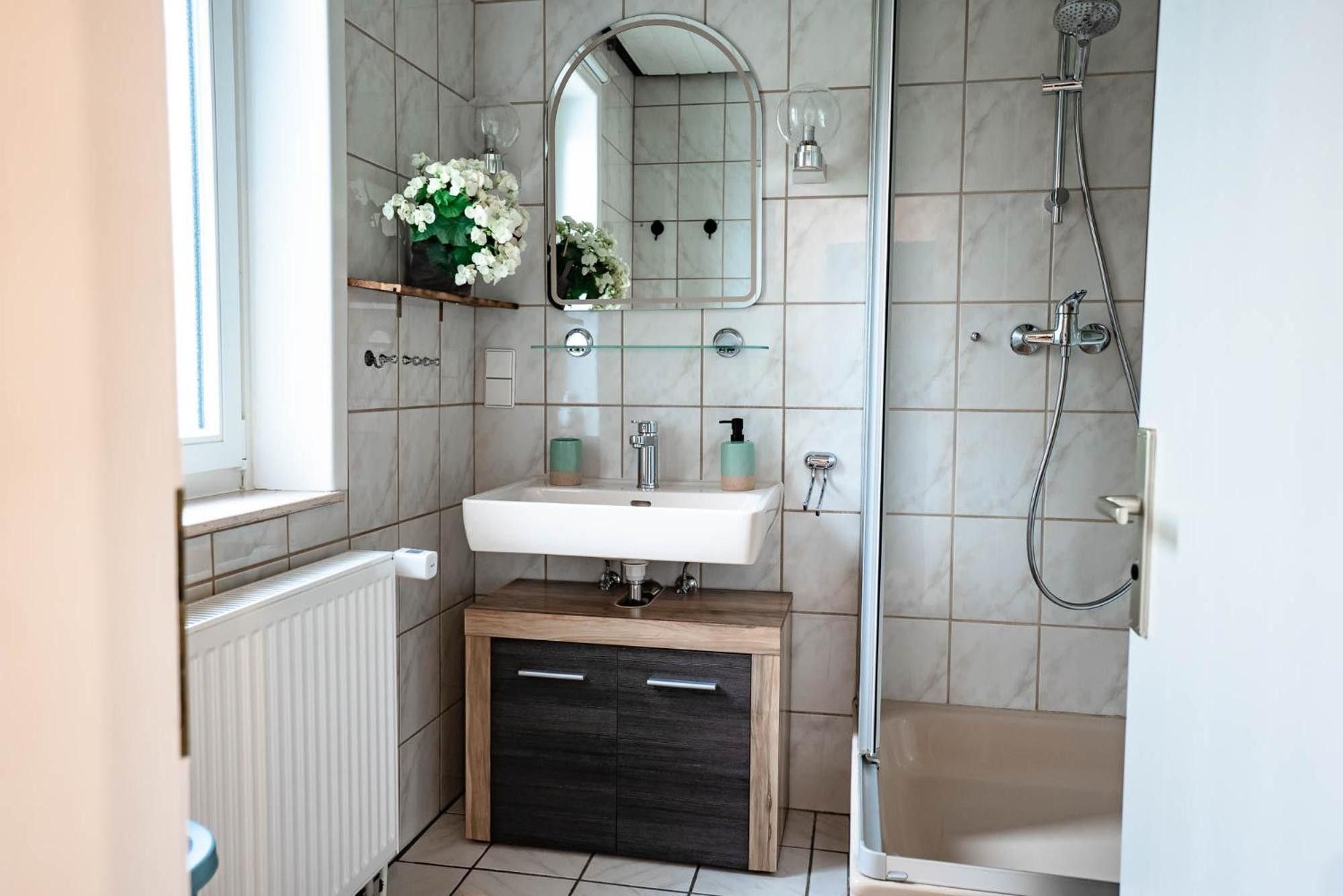 Ein Badezimmer mit Waschbecken, Spiegel, Dusche und Toilette.