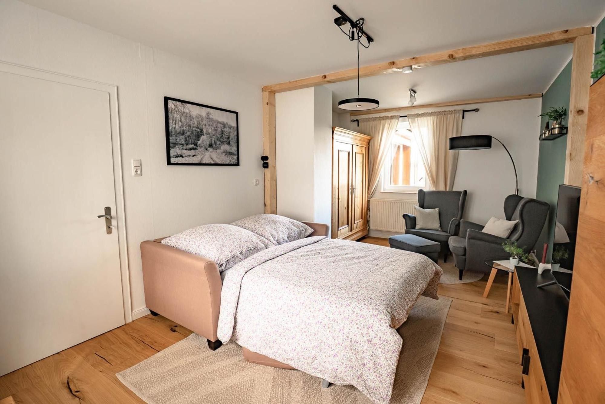 Un dormitorio con cama, escritorio, silla y ventana con cortinas.